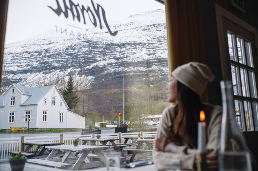 Looking out of a café window at a snow-covered mountain in Seyðisfjörður