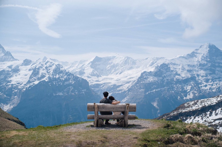Two people on a bench looking out at the Swiss Alps